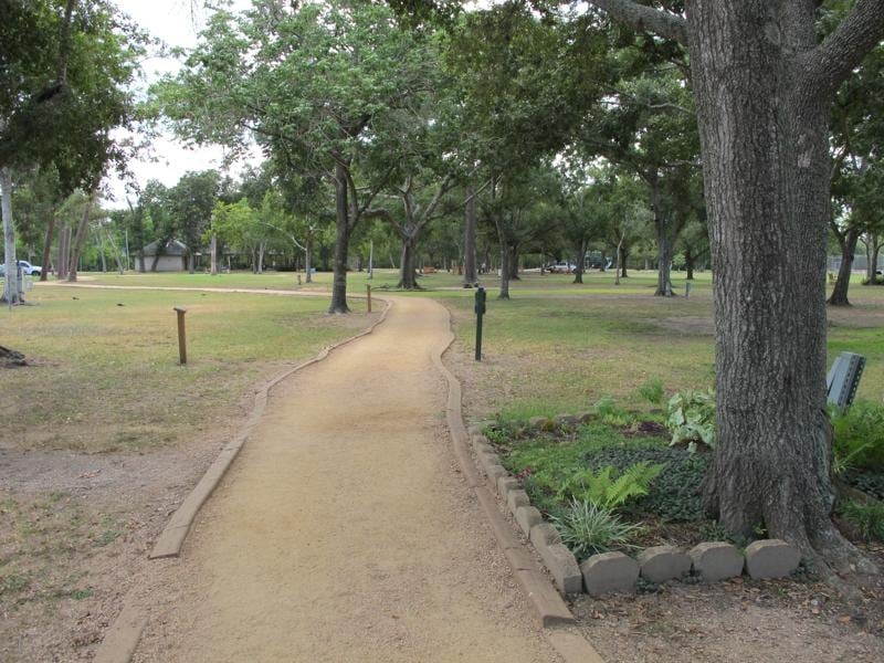 A shaded, tree-lined park path in Friendswood, TX