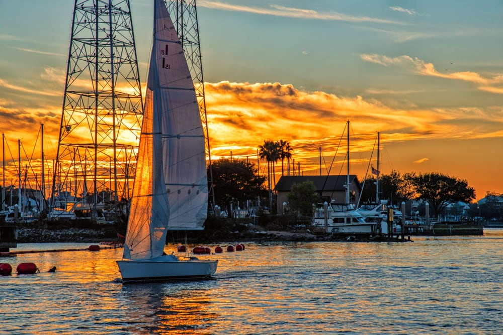 A sailboat silhouetted against a sunset in the Kemah, TX channel