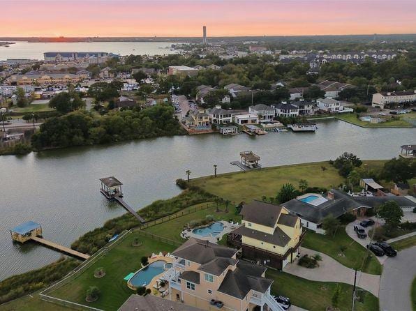 Aerial view of a Clear Lake waterfront neighborhood at dusk with the Houston skyline in the distance