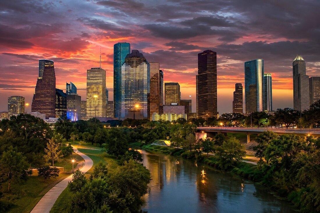 A footbridge over Buffalo Bayou with the Houston skyline at sunset